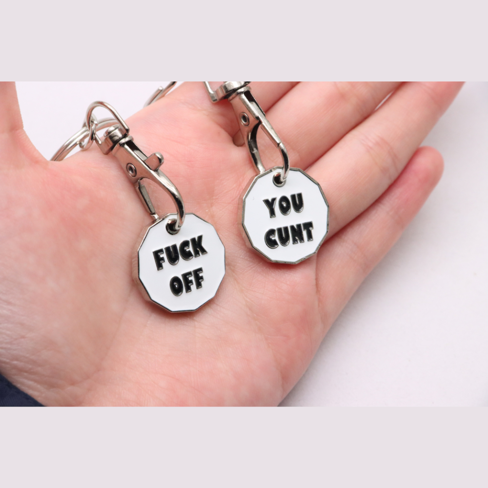 White octagonal enamel keychain tags with black bold lettering attached to silver metal clasps for trolley coins